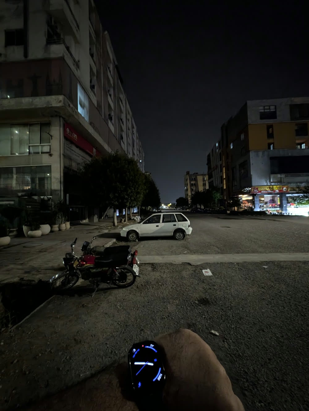 An empty street outside the office at night, a watch on the wrist